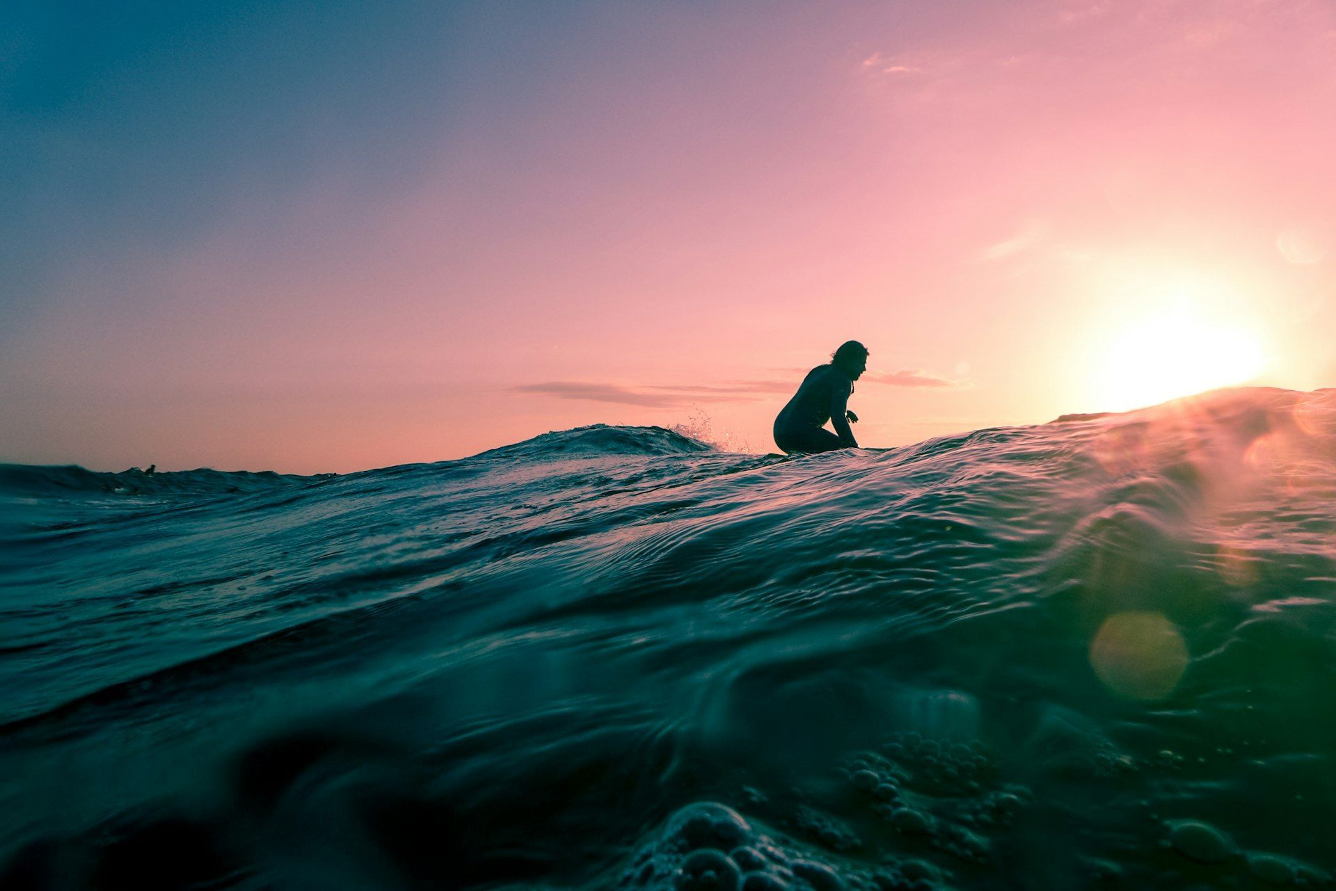 Surfer silhouette against pink sunset sky